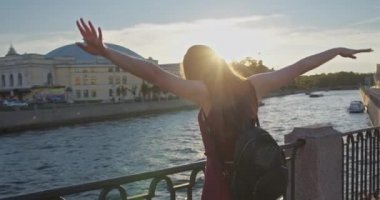 Sundress giymiş genç bir kız nehir kıyısında yürür.