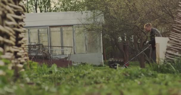 Grünes Gras im Garten und ein Mann mit Rasenmäher kommt in Zeitlupe vorbei — Stockvideo