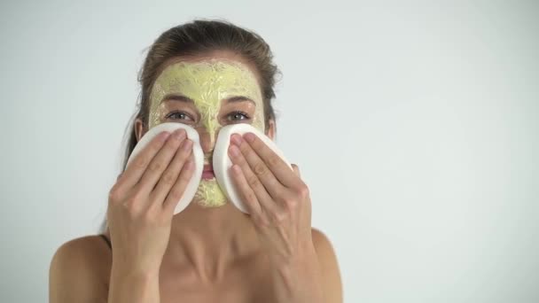 Het meisje verwijdert het masker van haar gezicht met een spons. Cosmetologische procedure. — Stockvideo