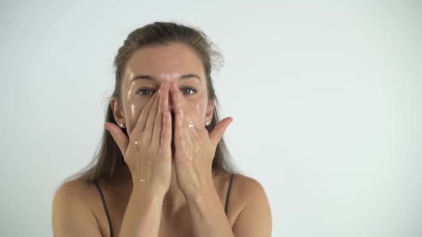 Jeune jolie fille applique de la crème sur la peau du visage. Massage du visage. — Video