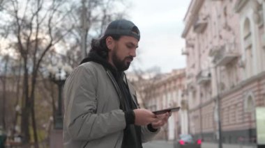 Güneşli bir sonbahar gününde, şehir sokağında telefonu olan genç yakışıklı bir adam..