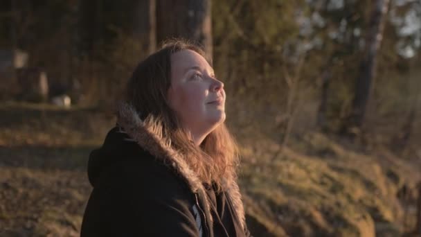 A young, plump beautiful girl at sunset by the lake in the rays of the sun — Stock Video