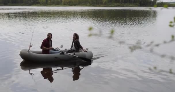 Jovens pescadores em um barco inflável no lago estão pescando. Fotografia cinematográfica. — Vídeo de Stock