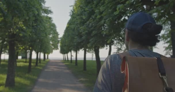 Osamělý cestovatel s batohem kráčí po stezce v parku u moře — Stock video