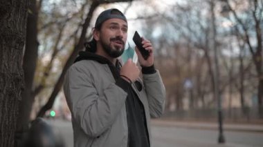 Güneşli bir sonbahar gününde, şehir sokağında telefonu olan genç yakışıklı bir adam..