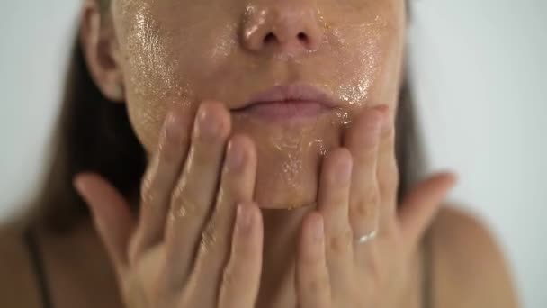 En ung vacker flicka applicerar en transparent fuktgivande mask på ansiktet. — Stockvideo