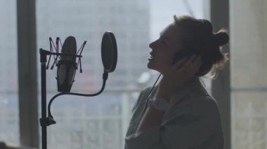 Genç bir kız duygusal olarak arka plandaki mikrofona şarkı söylüyor.