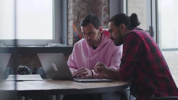 En ung affärsman med en bärbar dator pratar med en kollega, på kontoret — Stockvideo