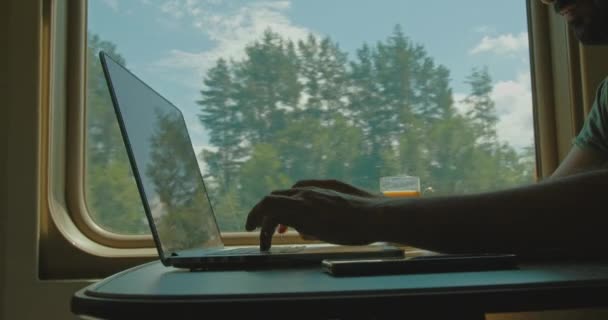 Close-up de mãos no teclado do laptop pela janela em um trem em movimento. — Vídeo de Stock