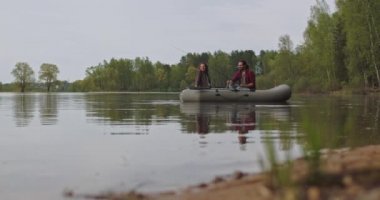 Göldeki şişme bir teknede genç balıkçılar balık tutuyor. Sinematik çekim.