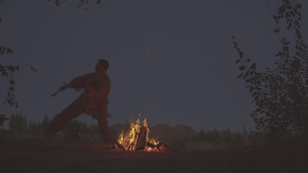 Un chaman avec un tambour saute autour du feu en vêtements pour la cérémonie. — Video