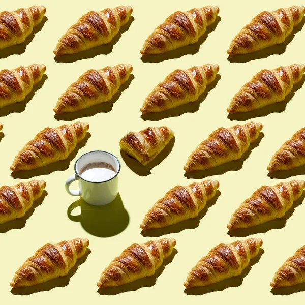 Kruvasan ve kahve fincanının az sarı arkaplanlı şekli. Üst görünüm, düz görünüm, modern asgari resim kavramı