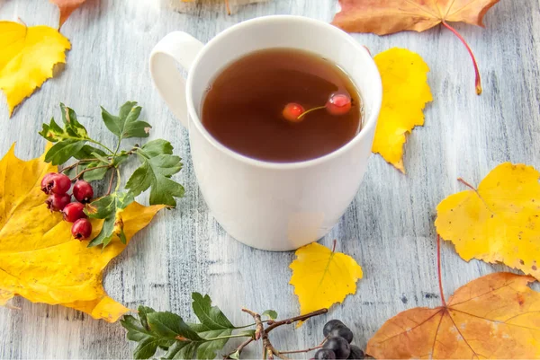 Осенний Фон Чашкой Чая Ягодами Желтыми Листьями Окрашенной Деревянной Поверхности — стоковое фото