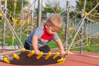 Küçük bir çocuk oyun alanında hevesle oynuyor. Başarı, yaratıcı fikirler ve spor kavramları. Çocuk parkı. Oyunlar.