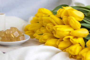 Bir buket taze sarı lale kahve ve ev yapımı marmelat ile kahvaltı. Yatakta kahvaltı. Bahar çiçekleri. Bahar ve tatil konsepti, 8 Mart, Uluslararası Kadınlar Günü, doğum günü. 