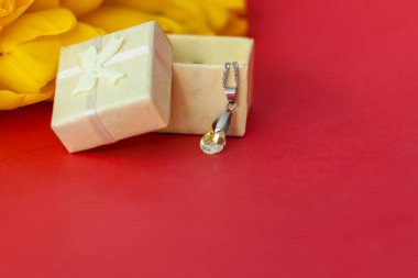 Kırmızı arka planda bir buket taze sarı lale. Lalelerin yanında küçük bir hediye kutusu. Bahar çiçekleri. Bahar ya da tatil konsepti, 8 Mart, Uluslararası Kadınlar Günü, doğum günü.