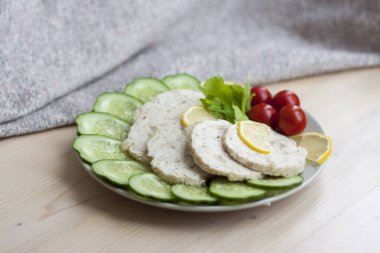 Fırında pişmiş tavuğun etini dilimlere ayır. Fırında pişirilmiş tavuk eti, salatalık ve vişneli domatesle birlikte bir tabağa konur. Ev yapımı tavuk sosisi.. 