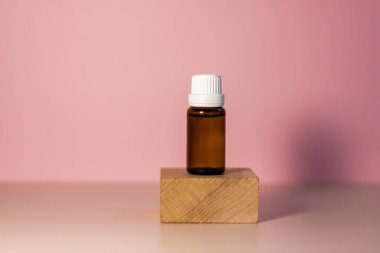 Kürsüde yağlı etiketsiz bir şişe. Bej-pembe arka planında şeker kutusu olan şeffaf cam bir kap. Ürün afişi. Metin ve tasarım için boşluk. Kozmetoloji ve güzellik kavramı 