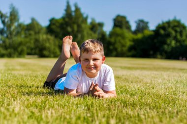 Neşeli bir çocuk neşeyle gülümser. Parktaki sıcak güneşli havada çimlerde yürümekten ve oynamaktan mutluluk duyarım. Çocukların yüzlerindeki duygular. mutluluk