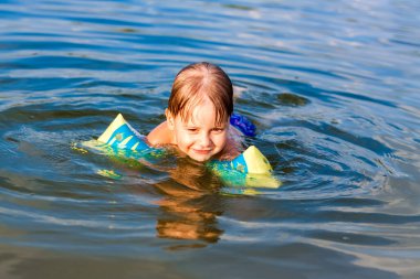 Çok sıcak bir yaz gününde mutlu bir çocuk nehirde yüzüyor. Su depolarında yüzmek. Mutlu bir aile yazın eğlenir ve suya su sıçratır. Aile tatilde.
