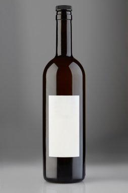 Kap ve gri arka plan üzerinde boş etiket ile kırmızı şarap şişesi