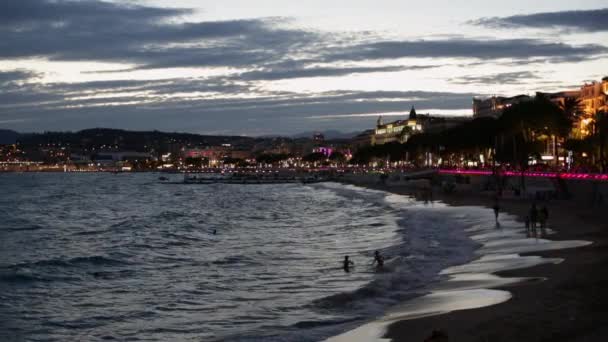 Φωτιζόμενο ακτή Κάννες και Croisette προβολή το βράδυ, άνθρωποι πάνω στη θάλασσα — Αρχείο Βίντεο