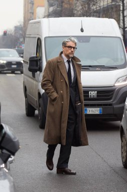 MILAN, ITALY - JANUARY 16, 2026: Man with brown coat and dark suit before Zegna fashion show, Milan Fashion Week street style
