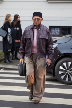 MILAN, ITALY - JANUARY 16, 2026: Man with purple leather jacket, beige, large trousers and Dior bag before Zegna fashion show, Milan Fashion Week street style