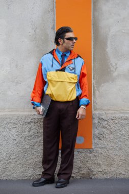 MILAN, ITALY - JANUARY 18, 2026: Man with yellow, orange and blue jacket and brown trousers before Prada fashion show, Milan Fashion Week street style
