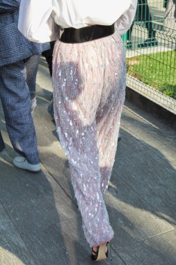 MILAN, İTALYA - 27 Şubat 2025: Emporio Armani defilesinden önce beyaz pembe pullu pantalonlu kadın, Milan Moda Haftası tarzı