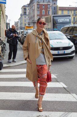 MILAN, İtalya - 28 Şubat 2025: Bej rengi uzun ceketli ve turuncu etekli kadın Sportmax defilesinden önce, Milan Moda Haftası tarzı
