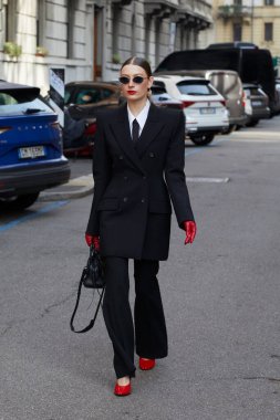 MİLAN, İTALYA - 28 Şubat 2025: Siyah takım elbiseli, kırmızı eldivenli ve ayakkabılı kadın Sportmax defilesinden önce, Milan Moda Haftası tarzı
