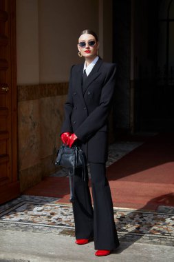 MİLAN, İTALYA - 28 Şubat 2025: Siyah takım elbiseli, kırmızı eldivenli ve ayakkabılı kadın Sportmax defilesinden önce, Milan Moda Haftası tarzı