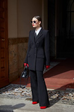 MİLAN, İTALYA - 28 Şubat 2025: Siyah takım elbiseli, kırmızı eldivenli ve ayakkabılı kadın Sportmax defilesinden önce, Milan Moda Haftası tarzı