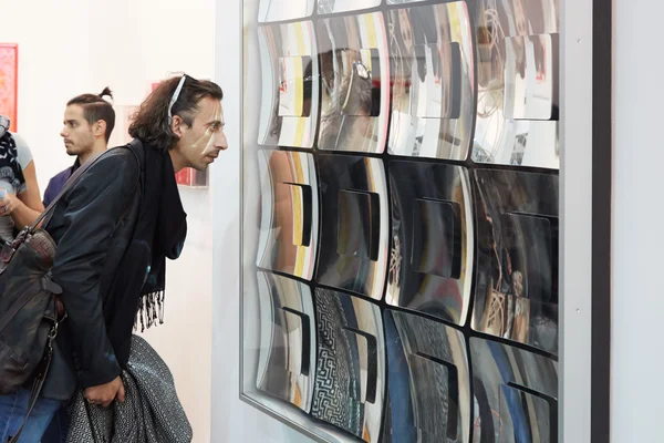 Artissima, contemporary art fair opening with man looking mirror artwork — стокове фото
