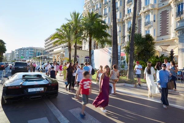 People walking in a summer afternoon under palm trees of the Croisette in Cannes