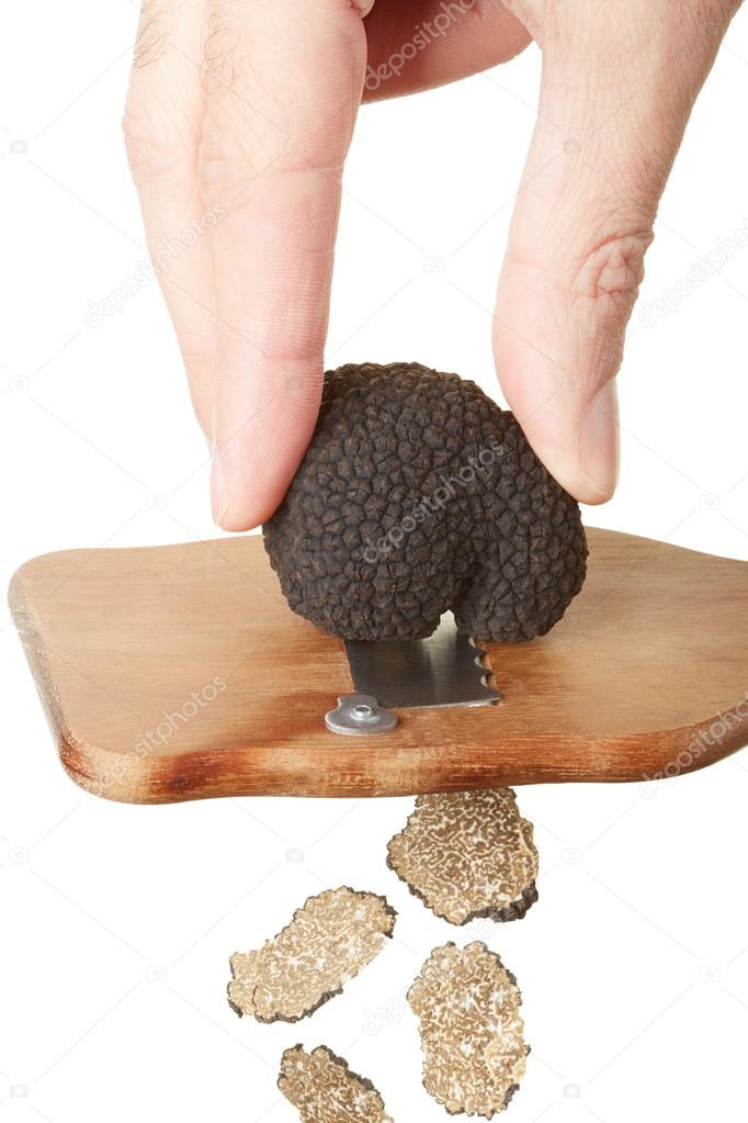 Hand slicing black truffle with wooden truffle slicer