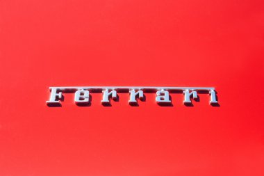 Silver Ferrari logo on red metal luxury car