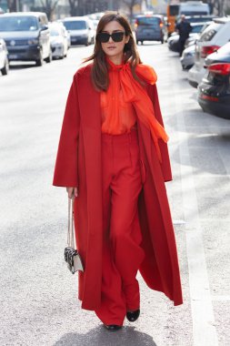 Eleonora Carisi poses for photographers with orange coat and trousers before Emporio Armani fashion show