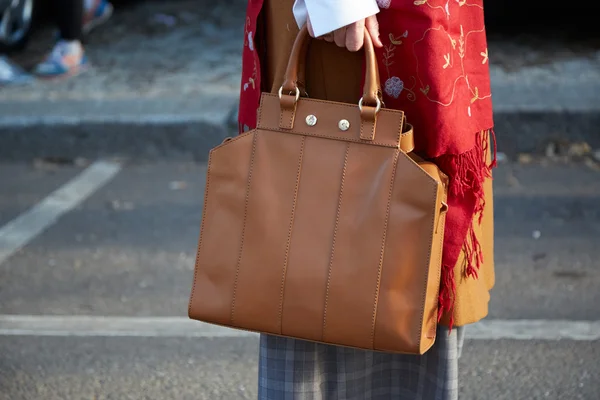 Žena představuje pro fotografy s hnědá kožená taška, pouliční styl — Stock fotografie