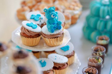 Mavili, kraliyet kremalı kek ve çikolatalı krema, katmanlı beyaz tabaklar ve bir bebek partisinde ya da bir çocuğun doğum günü partisinde lezzetli bir çöl barına hazırlanan tatlı ikramlar.