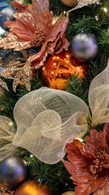 Altın ağ kurdeleleri, parıltılı küreler, büyük ipek noktalar, mevsimlik süsler ve iç mekanlara Noel tatili atmosferi sağlayan şenlikli kış ağacı süslemeleri.