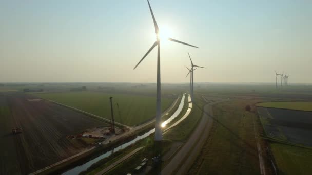 オランダ グローニンゲン州エームスハーフェンの日没時の電界中の風力タービン — ストック動画