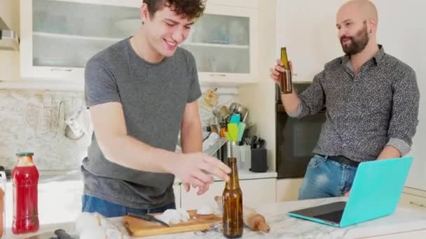 两个男人在厨房里用啤酒瓶做饭和祝酒 — 图库视频影像