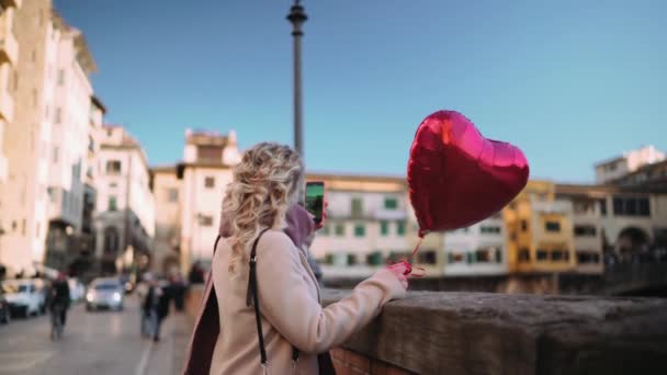 ビデオ通話付きのハート型の風船を持つ女性 フィレンツェ イタリア — ストック動画