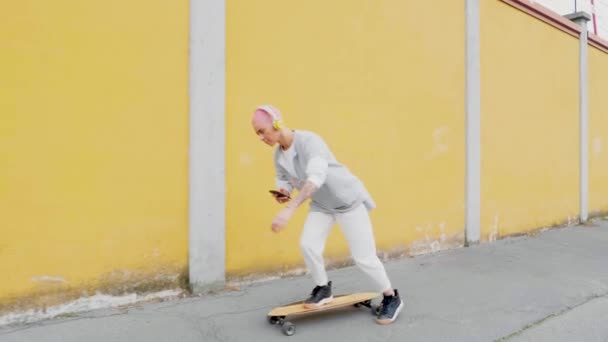 若い女性ロングボードスケートやスマートフォンで音楽を聴く — ストック動画