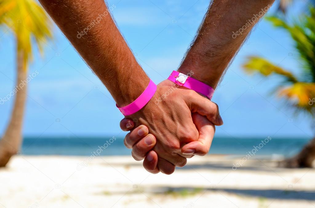 Gay couple on the beach holding hands. Gay men holding hands