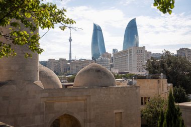 Tarihi mimarinin yanı sıra ikonik Ateş Kuleleri 'ni vurgulayan Bakü şehir manzarası büyüleyici bir manzara. Bu resim modern gökdelenlerle geleneksel taş yapılar arasında güzel bir tezat oluşturuyor.