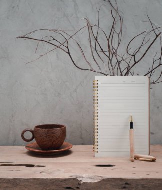 Hindistan cevizi kahve fincanı, kahverengi defter ve mercan ahşap vazoda, ahşap masa, tavan arası beton arka plan, ürünler için alan