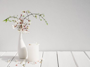 Beyaz mumlar ve modern cam vazodaki güzel Clerodendr çiçekleri beyaz ahşap masa odası iç kısmı, yaz yumuşak tonu durgun yaşam